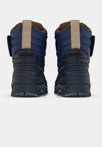Bottines bleu marine avec un design rembourré, semelles en caoutchouc texturé et accents beiges. Bandes velcro et logo sur le talon. Matériaux durables.