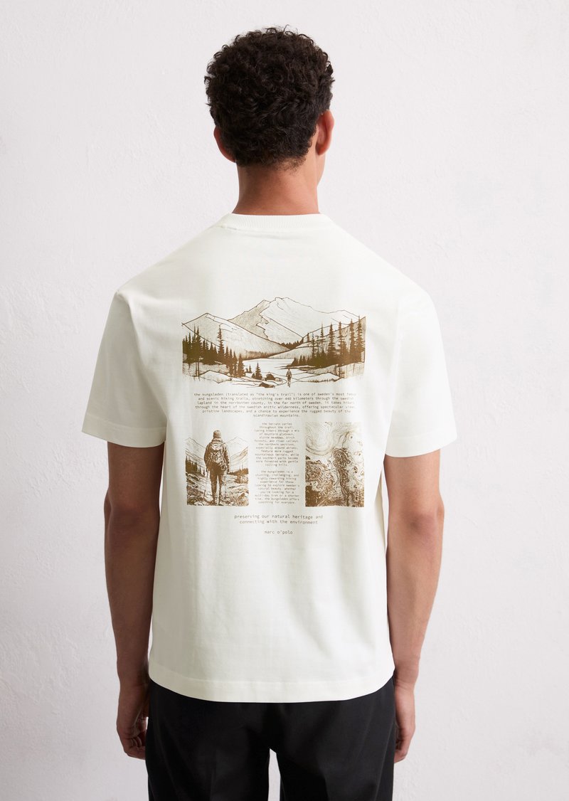 White cotton t-shirt featuring a brown graphic illustration of mountains, trees, and text on the back, with a crew neckline and short sleeves.