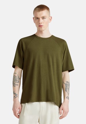 Camiseta de color verde oliva, de manga corta, con cuello redondo y mangas raglán, hecha de una tela suave. Presenta una textura sutil y un corte relajado.