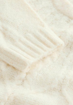 Cable-knit sweater in soft cream fabric. Textured surface with ribbed cuffs. Slightly fuzzy finish, showcasing intricate stitching patterns.