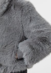 Sukienka z sztucznego futra w odcieniu szarym, o miękkiej, puszystej teksturze, z prążkowanymi mankietami i luźnym krojem, podkreślająca ciepło i komfort.