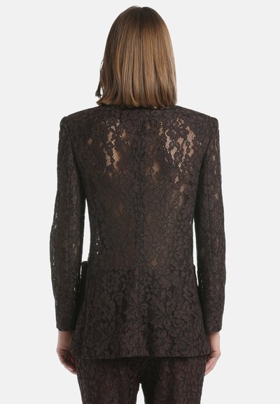 Blazer din dantelă de culoare maro închis, cu un design ajustat, mâneci lungi și modele florale. Dispune de o margine dreaptă și o spate ajustat.