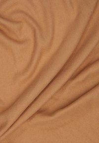 Tissu doux à côtes dans une teinte orange terreuse chaleureuse, présentant une texture lisse et un éclat subtil, avec des plis et des drapés délicats.