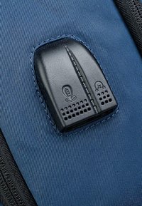 Panel de control de plástico negro sobre una tela azul texturizada, con íconos y un patrón perforado, integrado en un borde duradero con cremallera.