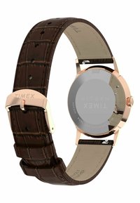 Timex-klocka med ett brunt läderarmband i krokodilsmönster, boett i roséguld och ett runt glaspanel.