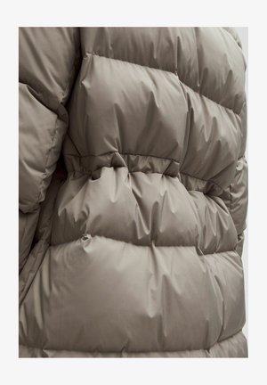 Puffer jacket in soft taupe fabric, featuring a quilted design with baffles, elastic waist, and smooth texture. No visible hardware.