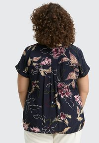 Blumenbluse mit kurzen Ärmeln, auf navy Hintergrund, mit großen rosa und cremefarbenen Blumen, aus weichem Stoff und in lockerer Passform mit Falten.