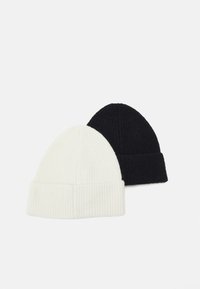 Two beanie hats, one white and one black, featuring a ribbed texture and folded brim design. Soft knit material.