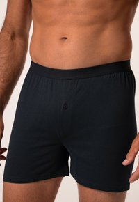 Černé bavlněné boxery s měkkým pasem a jedním knoflíkem vpředu, s hladkou texturou a pohodlným střihem.