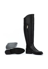 Botas de cuero negro hasta la rodilla con un acabado suave, que cuentan con un cierre lateral y suela plana. Una bota está en posición vertical; la otra yace de lado.