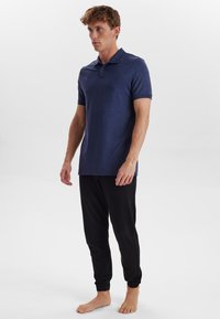 Námořnická polo košile vyrobená z texturované tkaniny, krátké rukávy a klasický límec, v kombinaci s černými úzkými joggery, elastickými manžetami a kapsami.