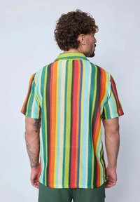 Chemise à manches courtes avec un motif rayé multicolore dans des tons de vert, rouge, jaune et bleu. Elle présente un tissu flexible et un col classique.