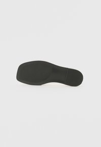 Schwarze Schuhsohle mit einer glatten, flachen Oberfläche und dezenten Grip-Mustern. Verfügt über eine runde Zehenpartie und ein minimalistisches Design.