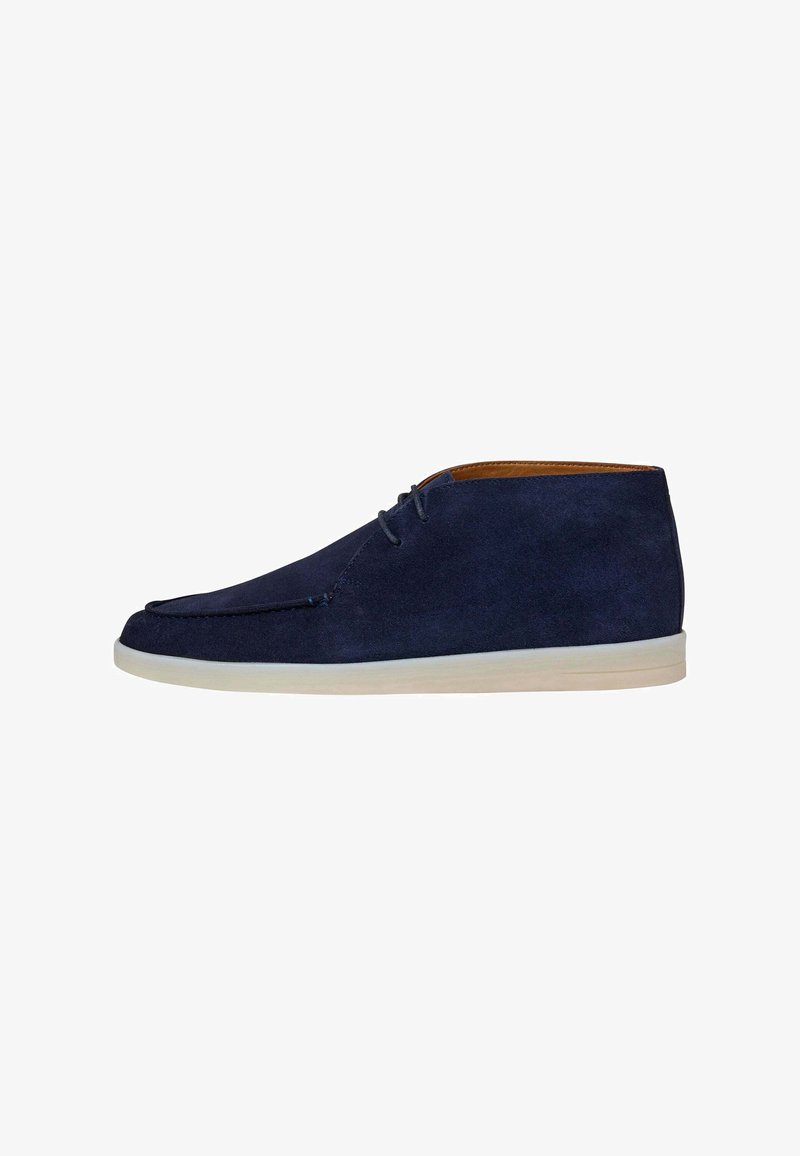 Dunkelblauer Wildleder-Herrenschuh im Chukka-Stil mit weißer Gummisohle und Schnürverschluss mit zwei Ösen, Seitenansicht vor weißem Hintergrund.