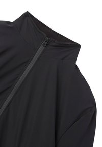 Giacca leggera nera con colletto alto, chiusura con zip e texture liscia. Presenta un design minimalista e un morbido bordo elastico attorno al collo.