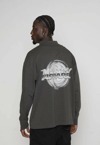 Ciemnoszara koszula z długim rękawem z dużą białą grafiką na plecach z napisem "MULTIPLY APPAREL". Prosty design, materiał z mieszanki bawełny.