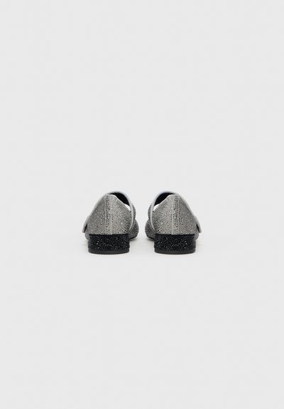 Silverfärgade ballerinaskor med strukturerad yta, svarta sulor och låg klack. Rundad tå med slät ovandel och subtila detaljer.
