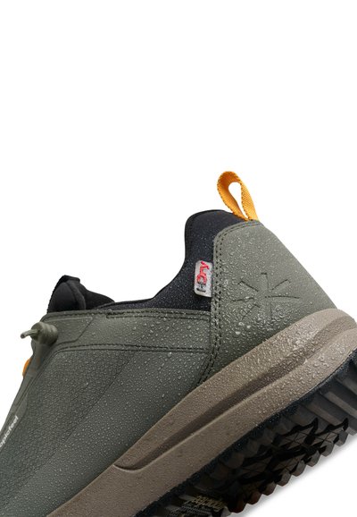 Gray waterproof sneaker with a textured surface, black accents, and an orange pull tab. Features rugged sole with grip patterns.