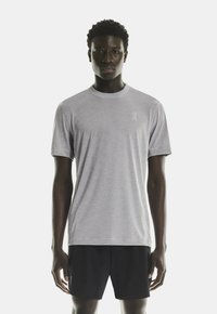 Lys grå atletisk T-shirt lavet af åndbart materiale, med rund halsudskæring og korte ærmer. Logo trykt på brystet.