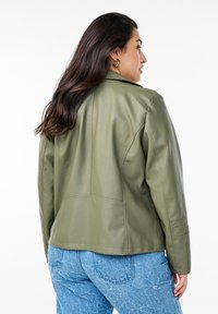 Olive green leather jacket featuring a fitted silhouette, structured shoulders, and side pockets, detailed with seam accents on the back.