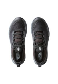 Scarpe sportive nere con tomaia in rete, suola in gomma grigia, lacci riflettenti e un logo prominente sulla linguetta. Design leggero.