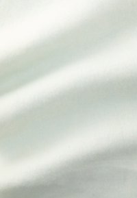 Puhá, fehér anyag sima textúrával, amelyen finom, világos színeltérések vannak, és lágy, hullámzós esés jellemzi.