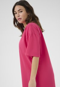 Růžové oversized tričko s krátkými rukávy, vyrobené z měkké bavlny. Jednoduchý design s volným střihem a kulatým výstřihem.