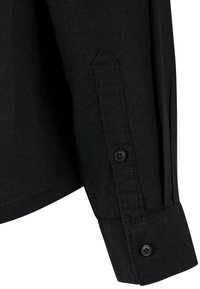 Black long-sleeve shirt cuff featuring a button closure, made from textured fabric with a straight-cut design and pointed cuff shape.