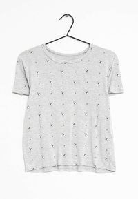 Camiseta gris de manga corta con un patrón repetido de pequeños pájaros. Confeccionada en tela suave, cuenta con un escote redondeado y un ajuste relajado.