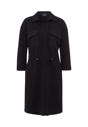 Zwart shirtjurk met een knoopsluiting aan de voorkant, twee borstzakken en een koordjes taille. Heeft driekwart mouwen en een gladde textuur.