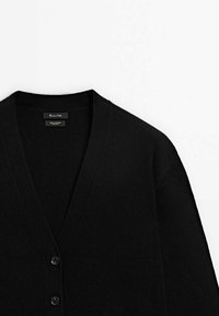 Cardigan en cachemire noir avec col en V et deux boutons à l'avant sur fond blanc.