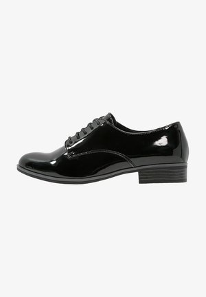 Chaussure oxford en cuir verni noir à lacets, avec un bout arrondi, une finition lisse et un petit talon empilé. Détails de surpiqûre simples sur le côté.