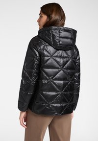 Chaqueta de plumón acolchada negra con capucha, que presenta un acabado brillante y un patrón de costura en diamante. Diseño ligero y estilizado.