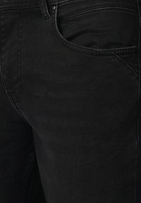 Czarne dżinsy o klasycznym pięciokieszeniowym kroju, z gładką fakturą i delikatnymi detalami przeszyć wzdłuż szwów.