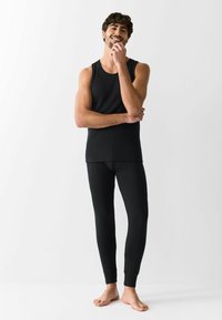 Canotta nera e leggings aderenti, entrambi con una texture liscia e un design classico. Materiale leggero, progettato per il comfort e la versatilità.