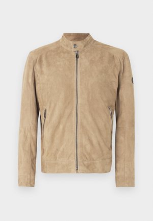 Veste en daim marron clair avec col montant, fermeture à glissière à l'avant, fermeture à boutons-pression, et poches latérales zippées, présentée sur fond blanc.