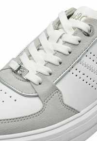 Baskets blanches et grises en cuir lisse et en suède, avec une forme arrondie, des lacets plats blancs, un design perforé et des détails en accent argent.