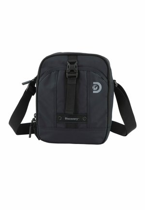 Bolso bandolera de nailon negro con cierre de hebilla, correa ajustable y logo en relieve en la parte frontal. Textura suave con diseño minimalista.