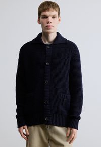 Tengerészkék kötött kardigán bordázott szegéllyel, túlméretezett gallérral, öt gombbal és két elülső zsebbel. Texturált szövet vastag szövésmintával.