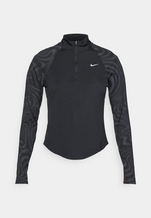 Maglietta atletica nera a maniche lunghe con zip a un quarto, caratterizzata da maniche a motivo a pois e logo Nike sul petto. Texture liscia.