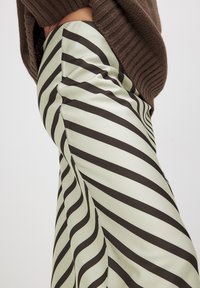 Stribet nederdel i en lys grøn farve med kraftige brune diagonale striber, lavet af et glat, skinnende materiale. Tætsiddende design.
