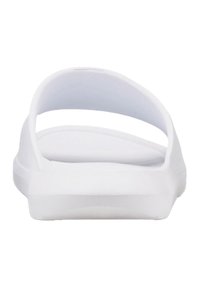 Hvide gummislidesandaler med et minimalistisk design, der har en bred strop og flad sål. Glat tekstur uden synlige mønstre eller accenter.