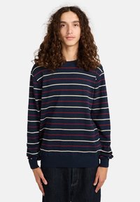 Maglione a righe blu navy con righe orizzontali bianche e rosse, collo rotondo, maniche lunghe e polsini e orlo a costine.