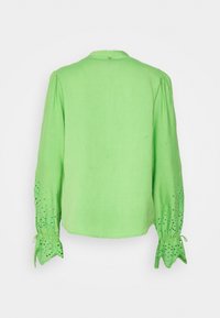 Blusa in lino verde con maniche lunghe dotate di dettagli a taglio e polsini arricciati, scollatura rotonda e chiusura con bottone sul retro.
