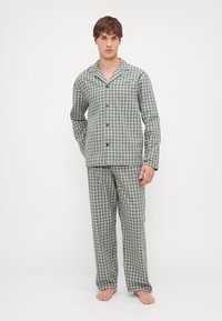 Conjunto de pijama a cuadros verdes y blancos con una camisa de botón de cuello y pantalones a juego, que presenta un corte relajado y una textura de tela suave.