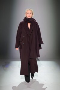 Ilgas, tamsiai burgundiškas paltas su dvigubu užsegimu, dideliais įstrižais atvartais ir atitinkama šaliku. Modelis vilki prigludusius juodus kelnes ir aukštakulnius.