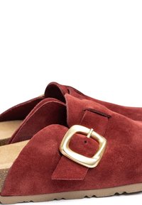 Sandale flottante en suède rouge, dotée d'une large sangle, de ferrures en or et d'une semelle en liège texturée avec une semelle extérieure en caoutchouc beige.