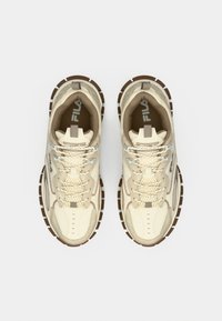 Μπεζ αθλητικά παπούτσια με υφή, στρογγυλή μύτη και καφέ λαστιχένια σόλα. Κορδόνια και διακοσμητικά σε πιο ανοιχτό μπεζ. Λογότυπο Fila στη γλώσσα.