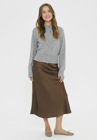 Grau gestrickte Strickjacke mit Knöpfen, brarocke Satin-Mittel Länge Rock und beigen flachen Schuhen mit Nietenakzenten. Glatte Texturen, lässige Passform.