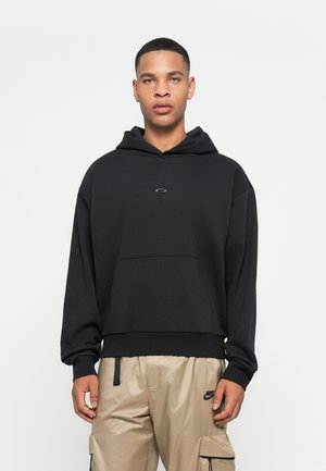 Zwarte hoodie gemaakt van zachte stof met een voorzak en een geborduurd logo op borsthoogte. Relaxte pasvorm met lange mouwen.